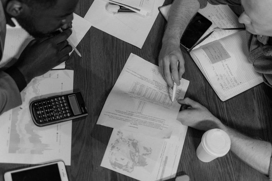 High angle view of a diverse team in a black and white financial planning meeting with documents.